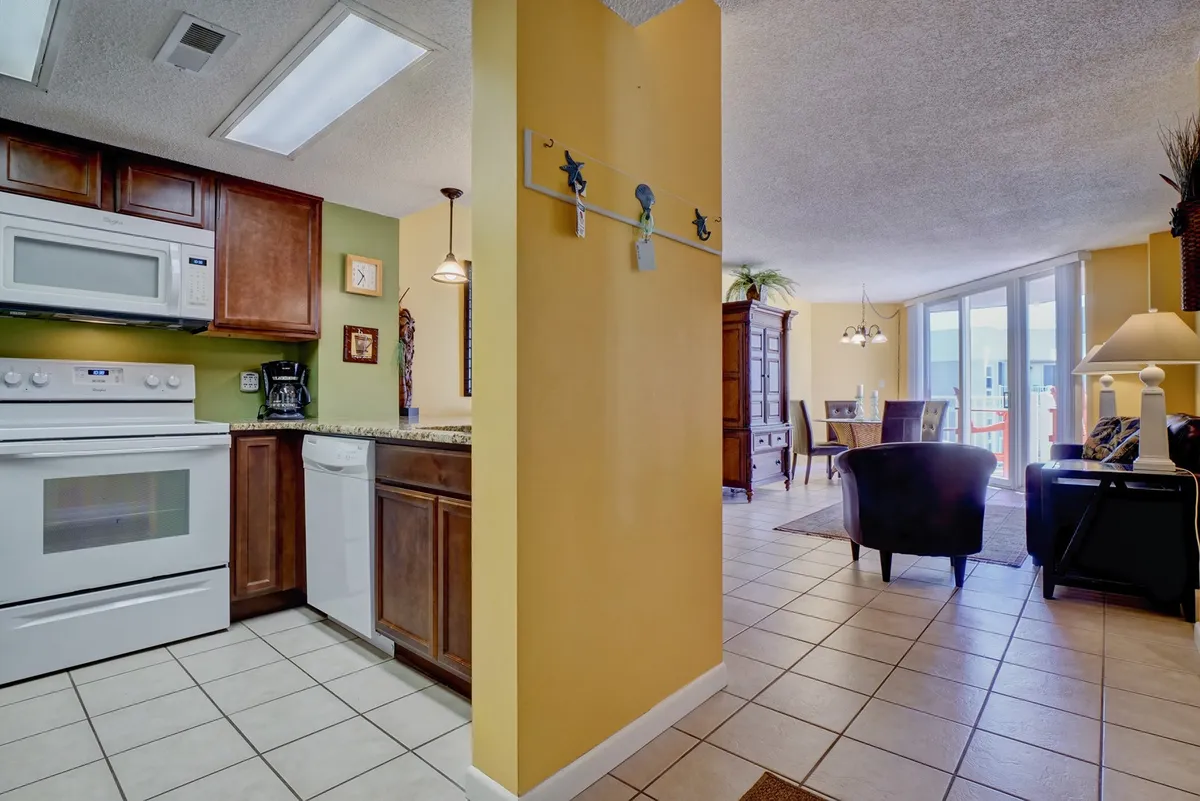 A spacious, homey open-plan kitchen, dining, and living area featuring modern kitchen appliances, a cozy dining area set for meals, comfortable living room seating, and decorative wall art. The room looks welcoming and supports shared dining and socializing.