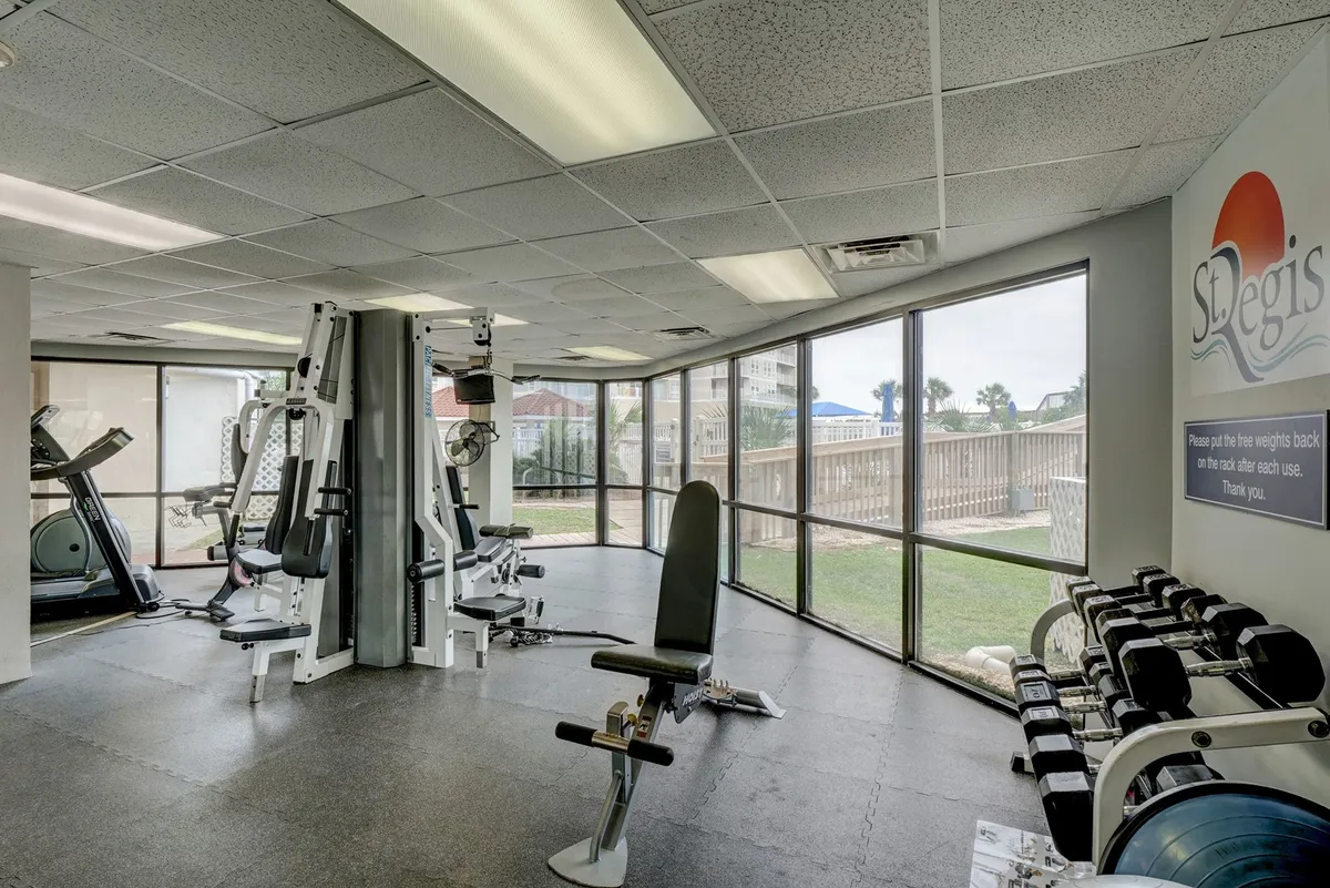 A bright, energetic fitness center featuring modern exercise equipment, plenty of natural light streaming through large windows, and fitness mats ready for group classes or personal workouts. The open layout encourages movement and social interaction while offering views of the outdoor surroundings.