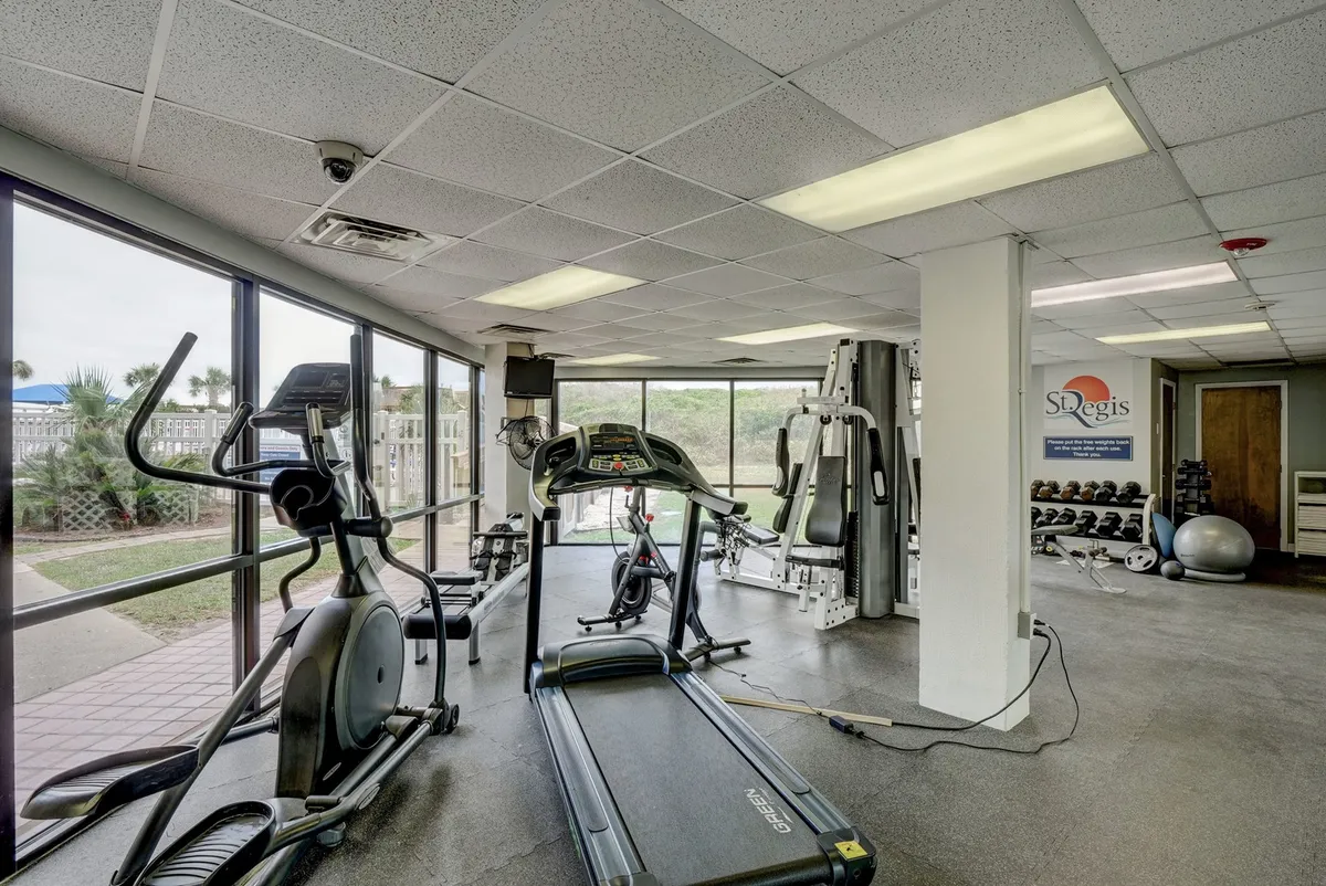 A bright, spacious fitness center filled with modern cardio and strength-training equipment, large windows letting in natural light, and a fitness ball in the foreground. The area feels energetic and motivating.